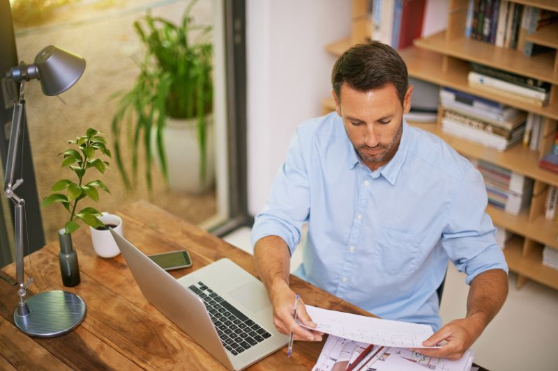 A man sits at a wooden desk, focused on reviewing, understanding and managing the lawful basis for data processing documents under the GDPR.