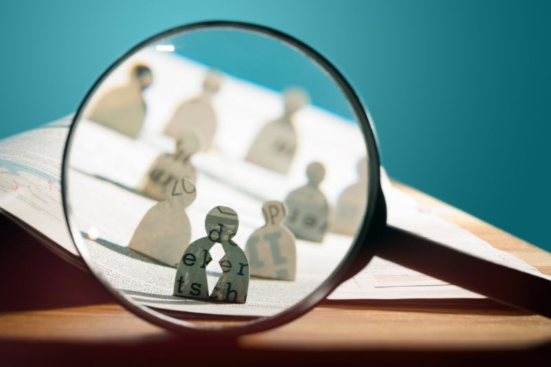 Magnifying glass focusing on paper figures, symbolizing a DPO’s role in GDPR compliance and data protection oversight